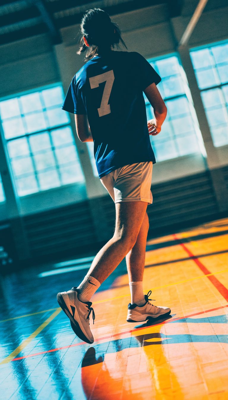 A volleyball player stepping onto the court, seen from behind